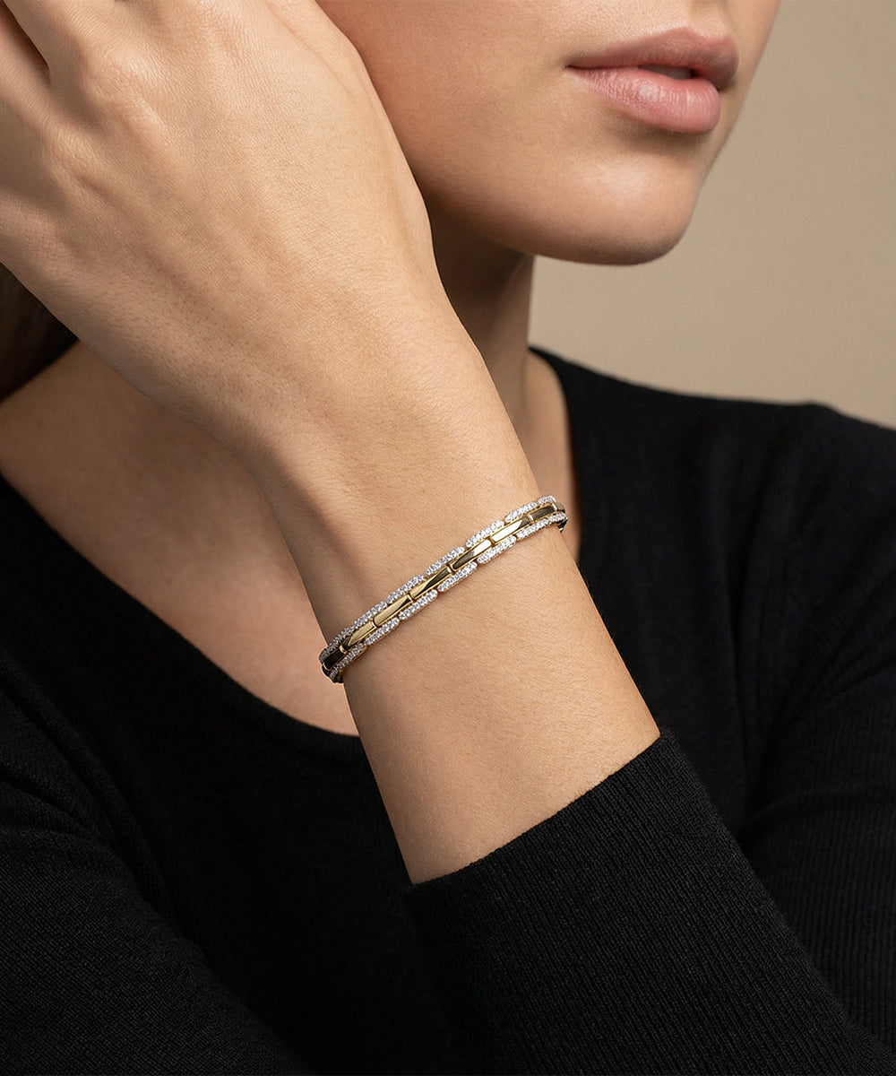 Close-up of a person wearing a silver bracelet on a neutral background