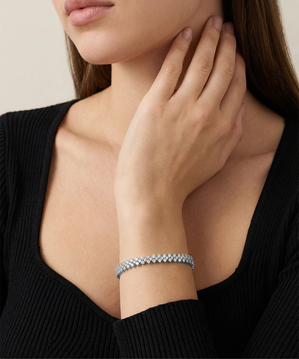 Woman wearing a silver bracelet on her wrist with a neutral background