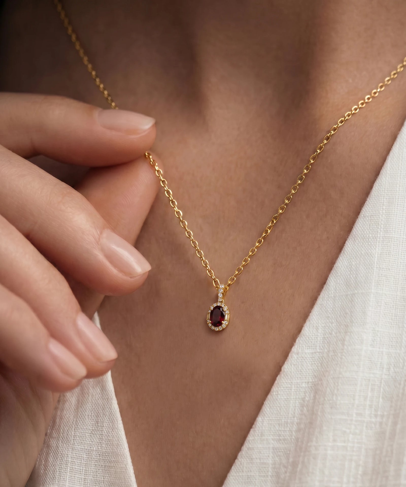 Gold necklace with a red gemstone pendant worn by a person