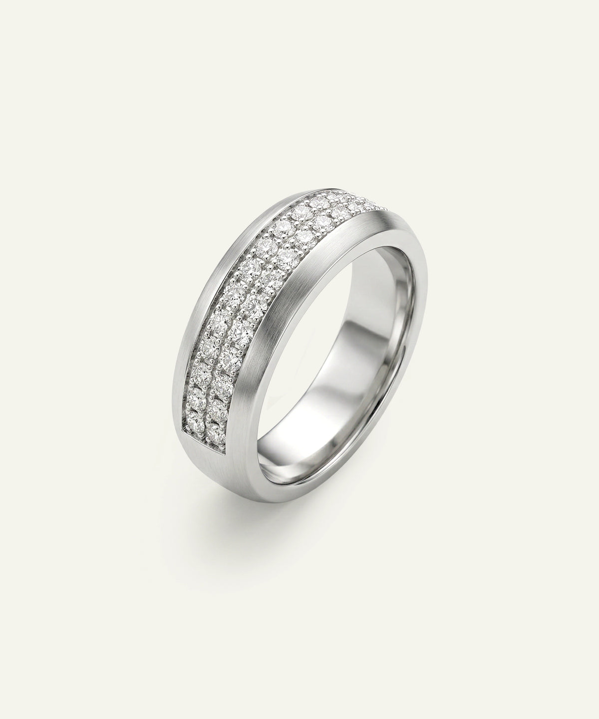 A silver-toned band ring featuring two parallel rows of small clear pavé stones on a light cream background.