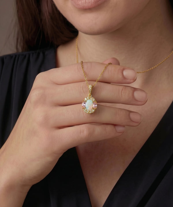Close-up of a person wearing a gold necklace with an opal pendant.