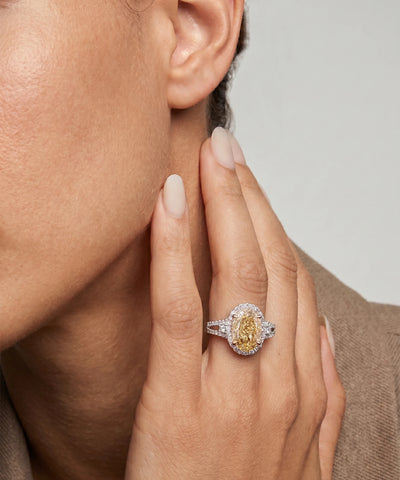 Close-up of a hand wearing a yellow diamond ring with a neutral background - alternate view