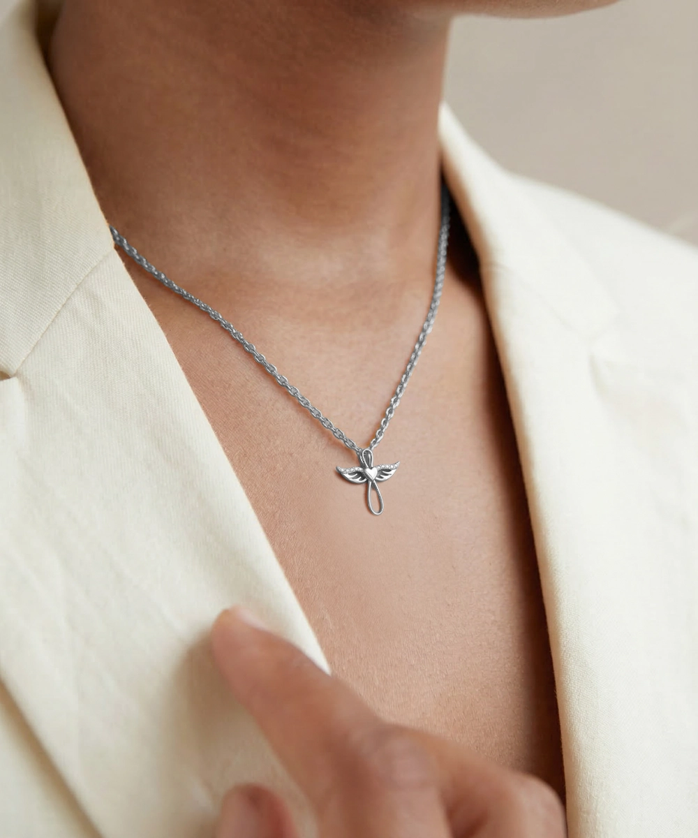 Silver necklace with a delicate pendant worn by a person in a cream blazer.