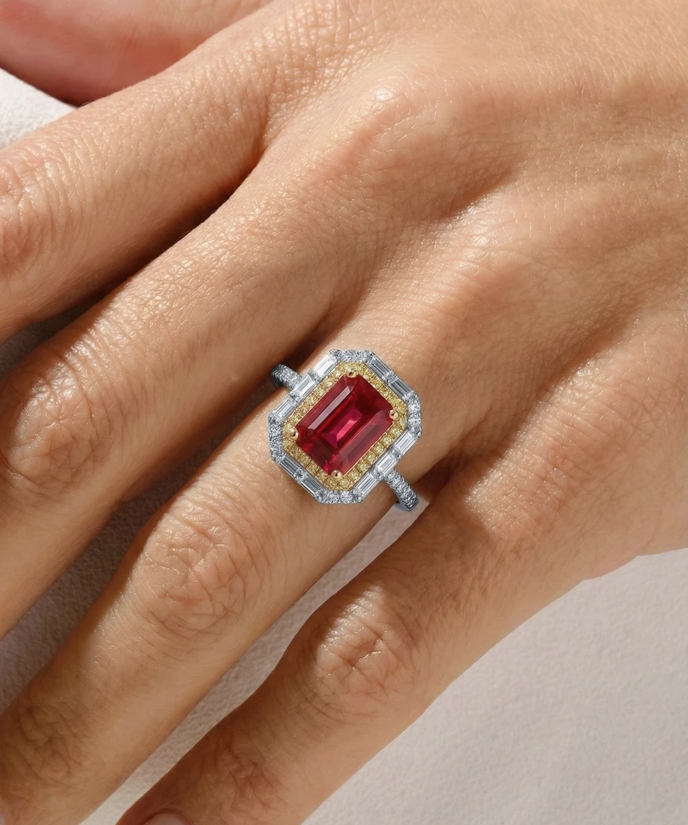 Ring with a red gemstone on a hand against a neutral background