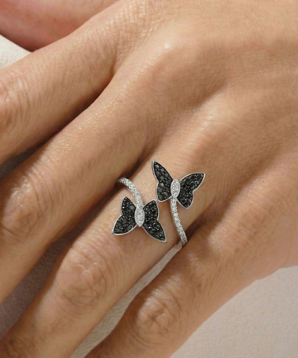 Butterfly-shaped ring with black and white gemstones on a hand