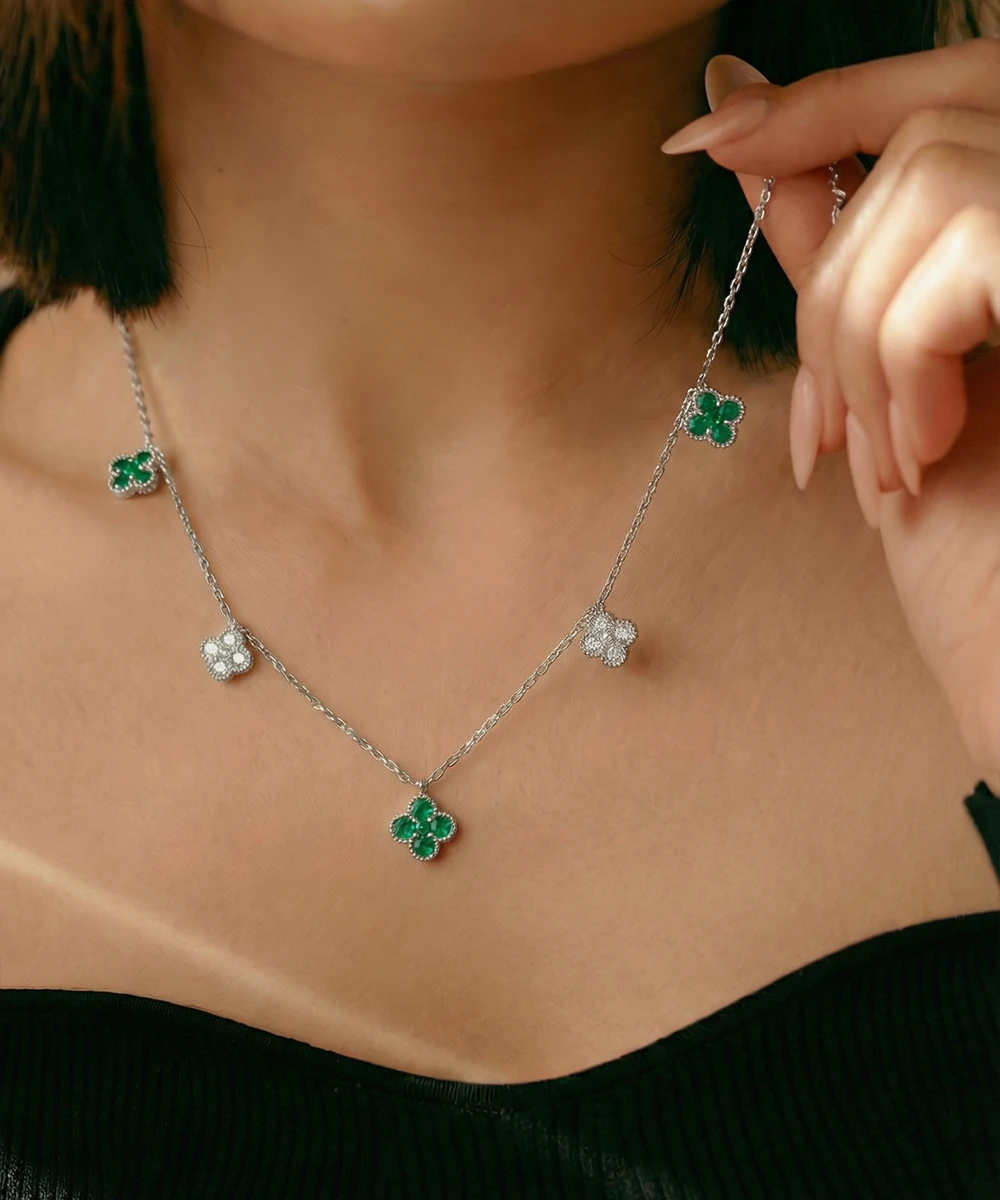 Necklace with green clover pendants being worn by a person