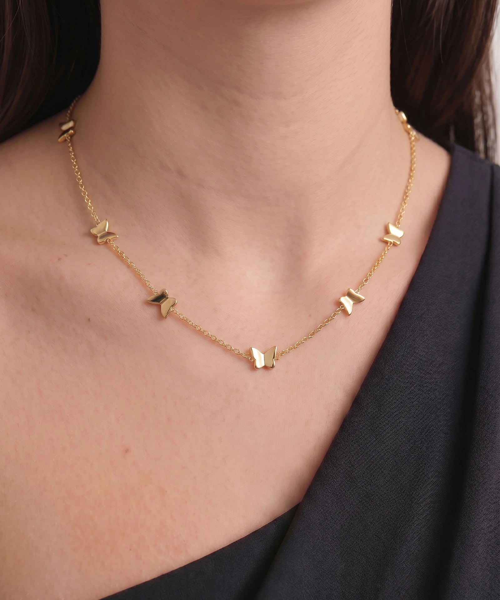 Gold necklace with heart-shaped pendants on a person wearing a black top.