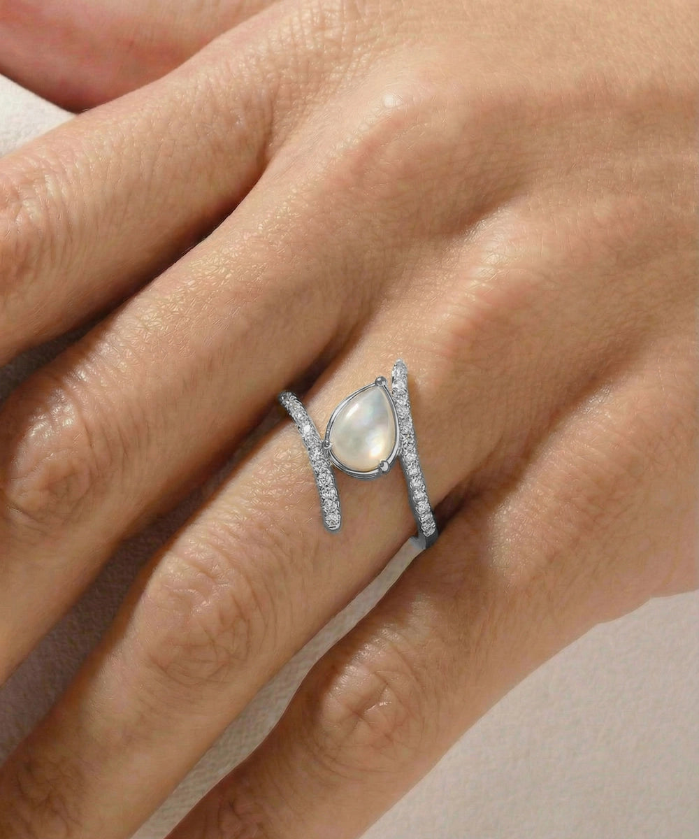 Silver ring with a central gemstone on a hand against a neutral background