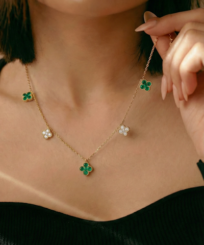 Necklace with clover-shaped pendants being adjusted by a hand - alternate view
