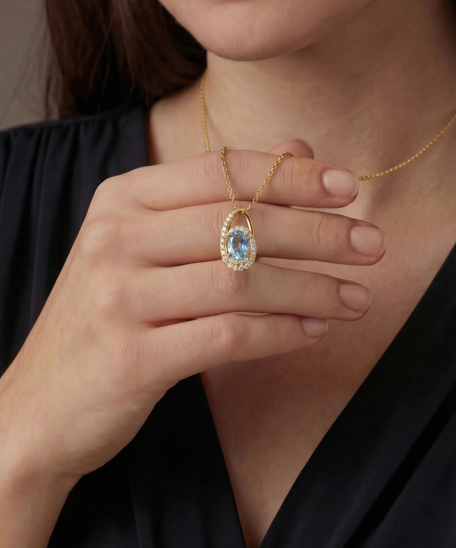Gold necklace with a green gemstone pendant worn by a person