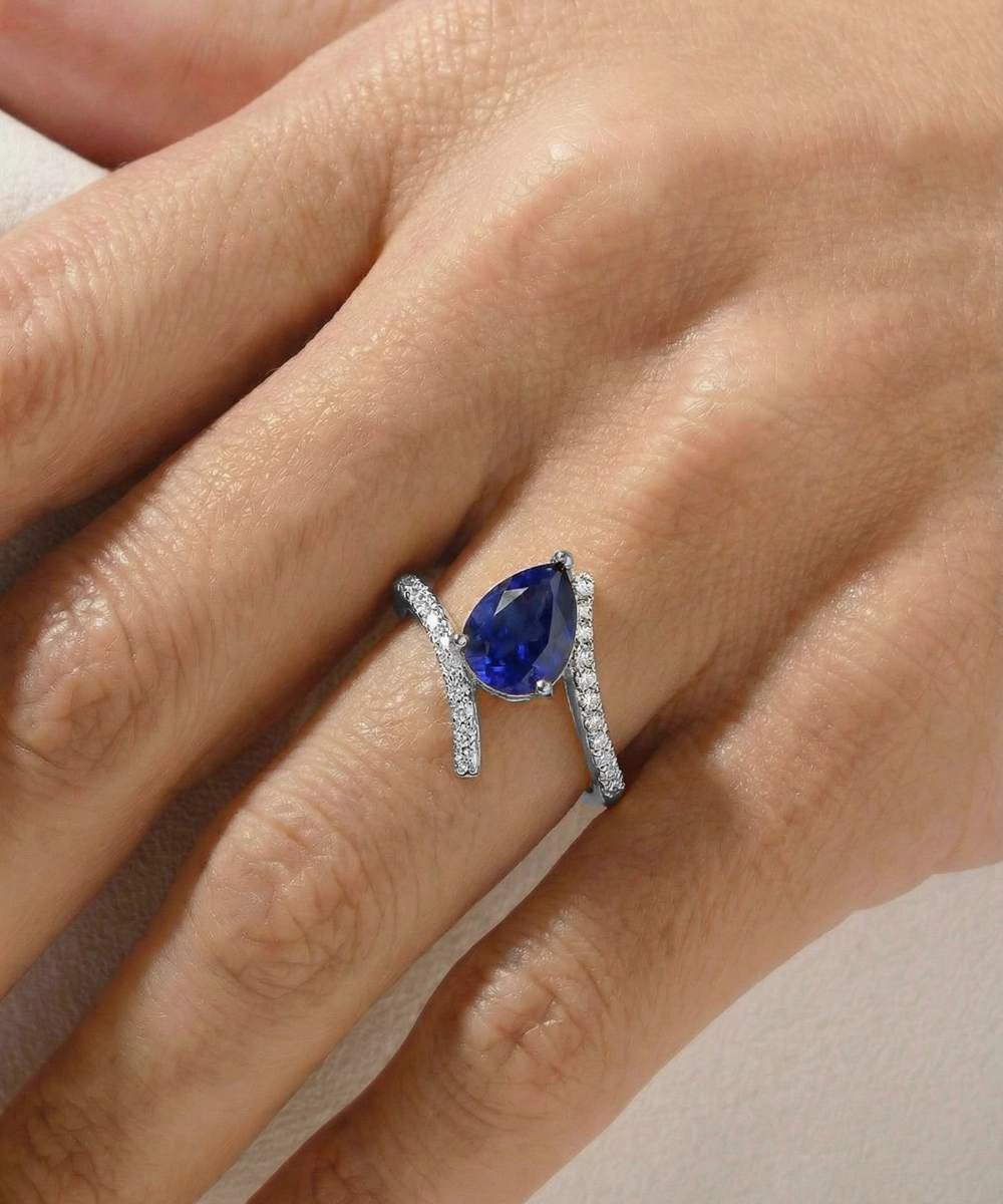 Blue gemstone ring with silver band on a hand