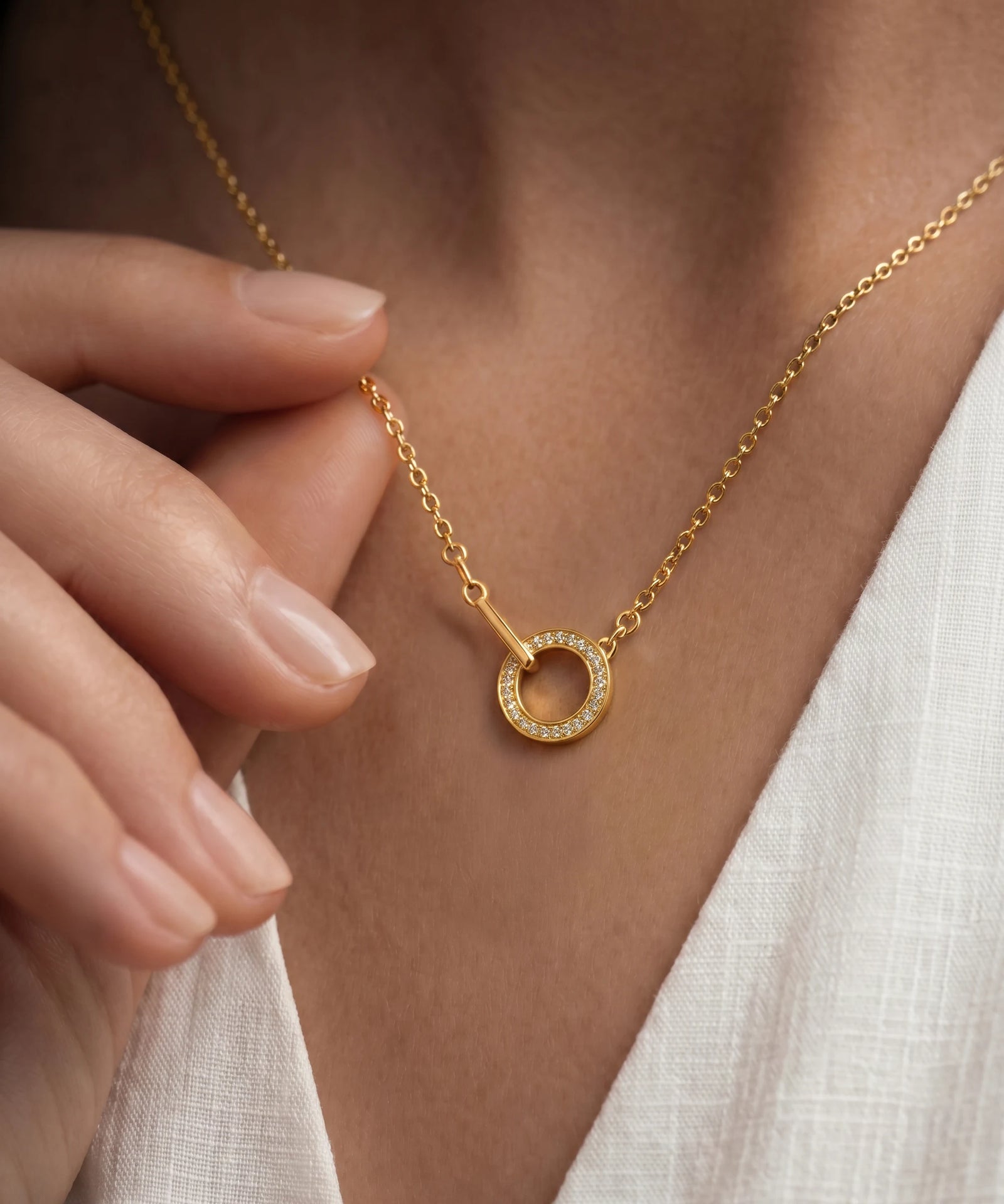 Gold necklace with a circular pendant worn by a person