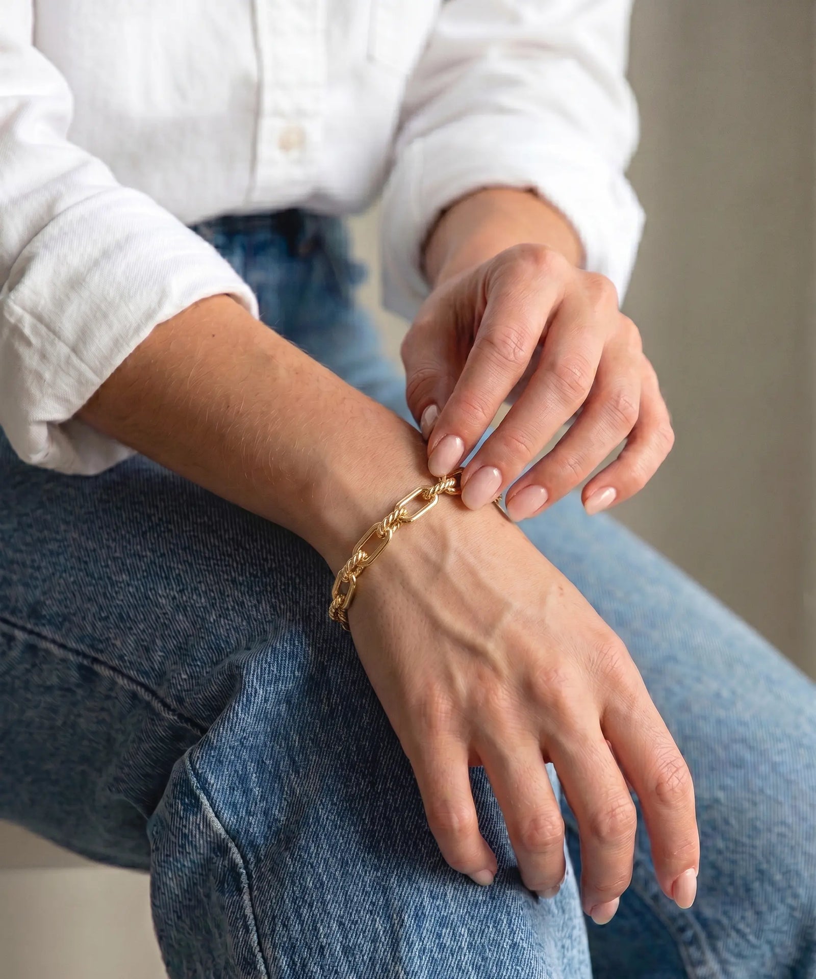Person wearing a gold bracelet on a blurred background