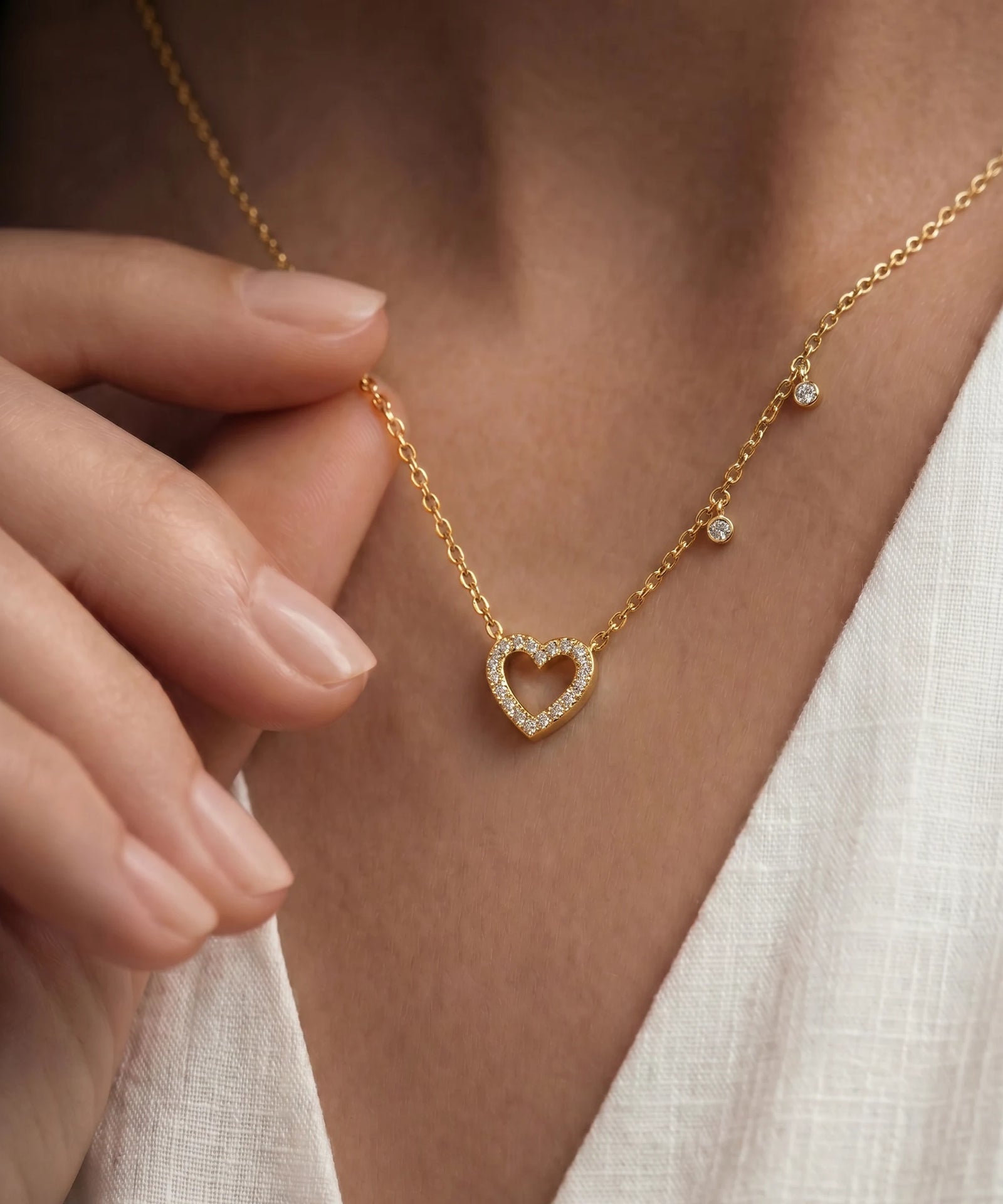 Gold necklace with a heart-shaped pendant worn by a person