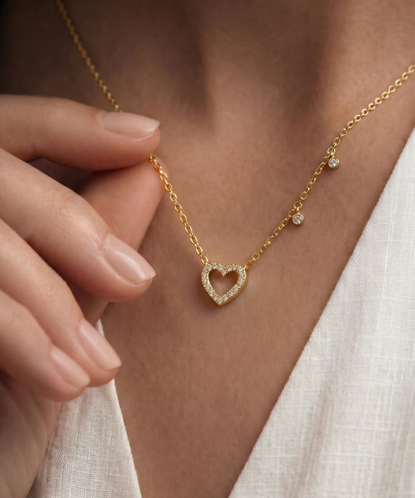 Gold necklace with a heart-shaped pendant worn by a person
