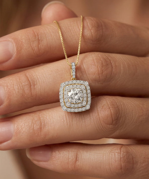 Gold necklace with a diamond pendant held between fingers