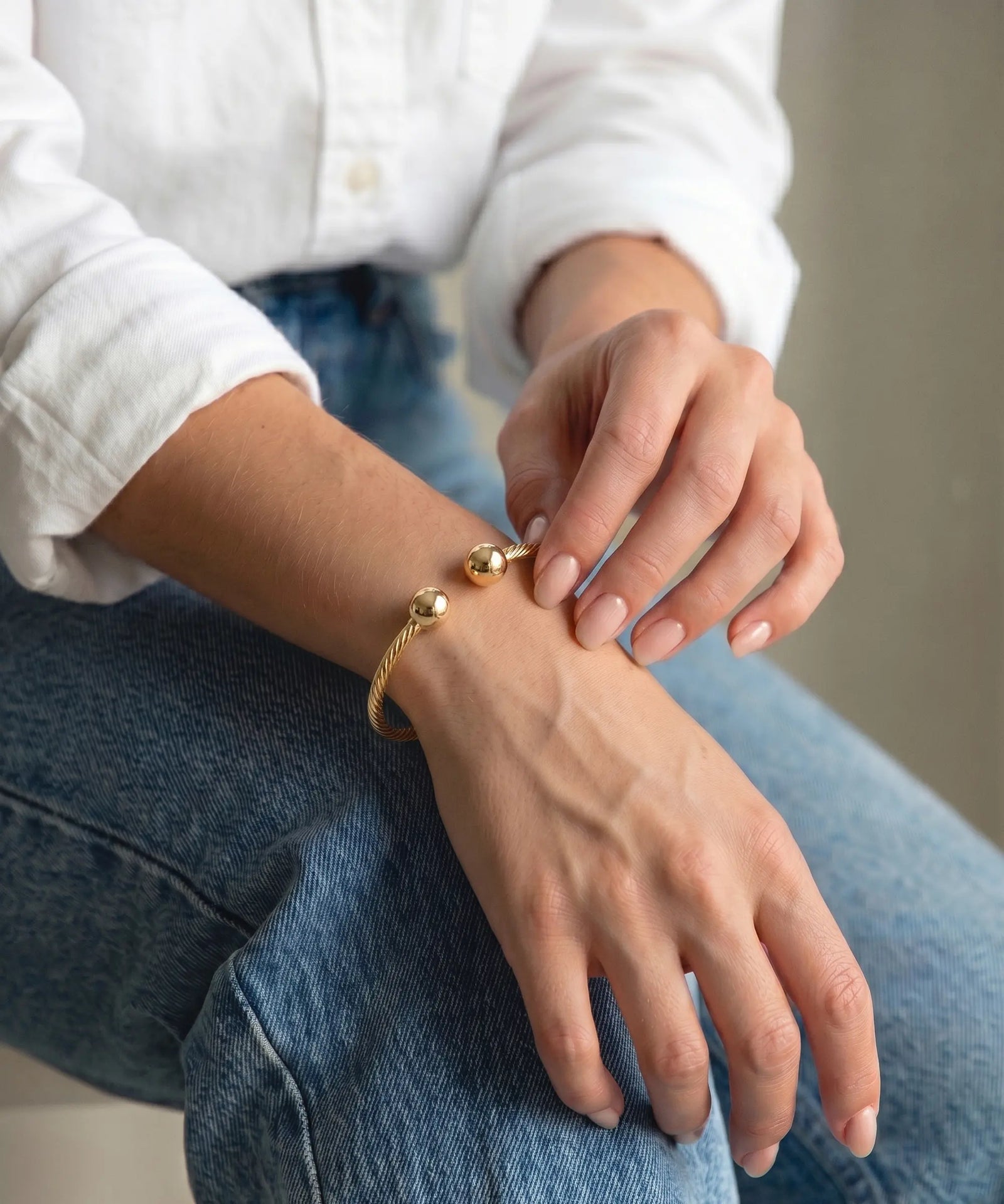 Person wearing a gold bracelet on a casual setting