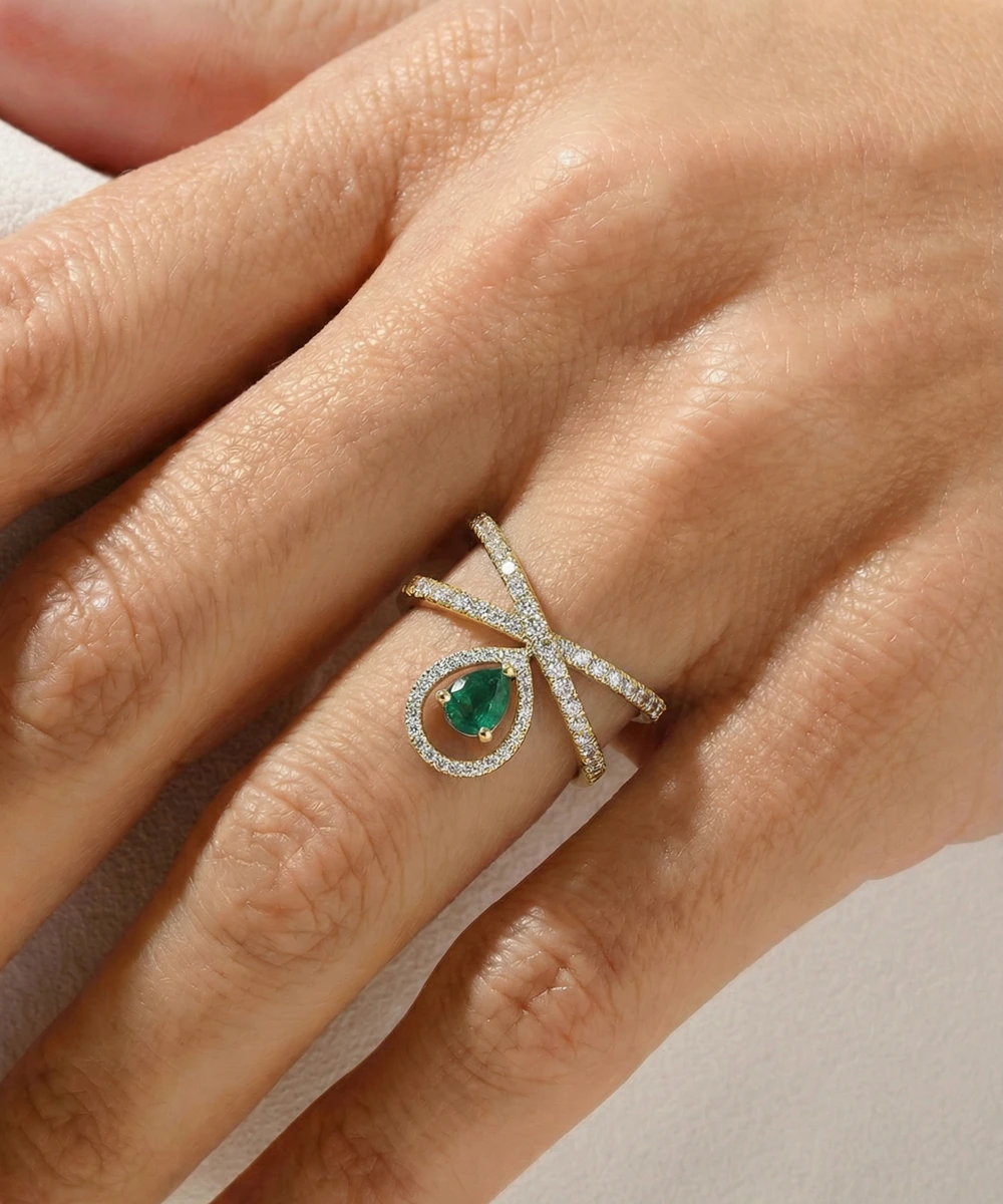 Silver ring with a green gemstone on a hand against a neutral background