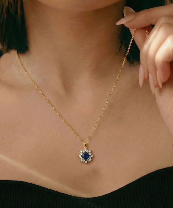 Gold necklace with a blue gemstone pendant worn by a person