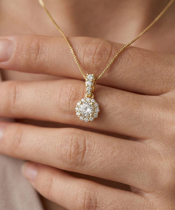 Gold necklace with a diamond pendant held by a hand