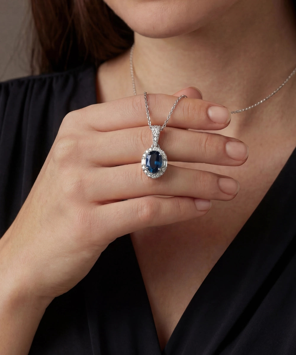 Person wearing a silver necklace with a blue gemstone pendant
