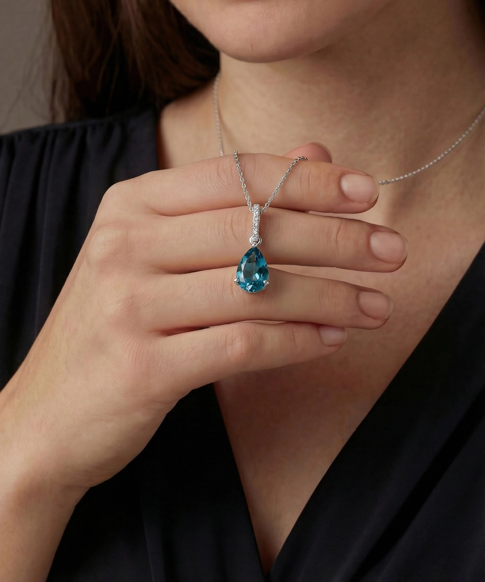 Person wearing a silver necklace with a blue gemstone pendant