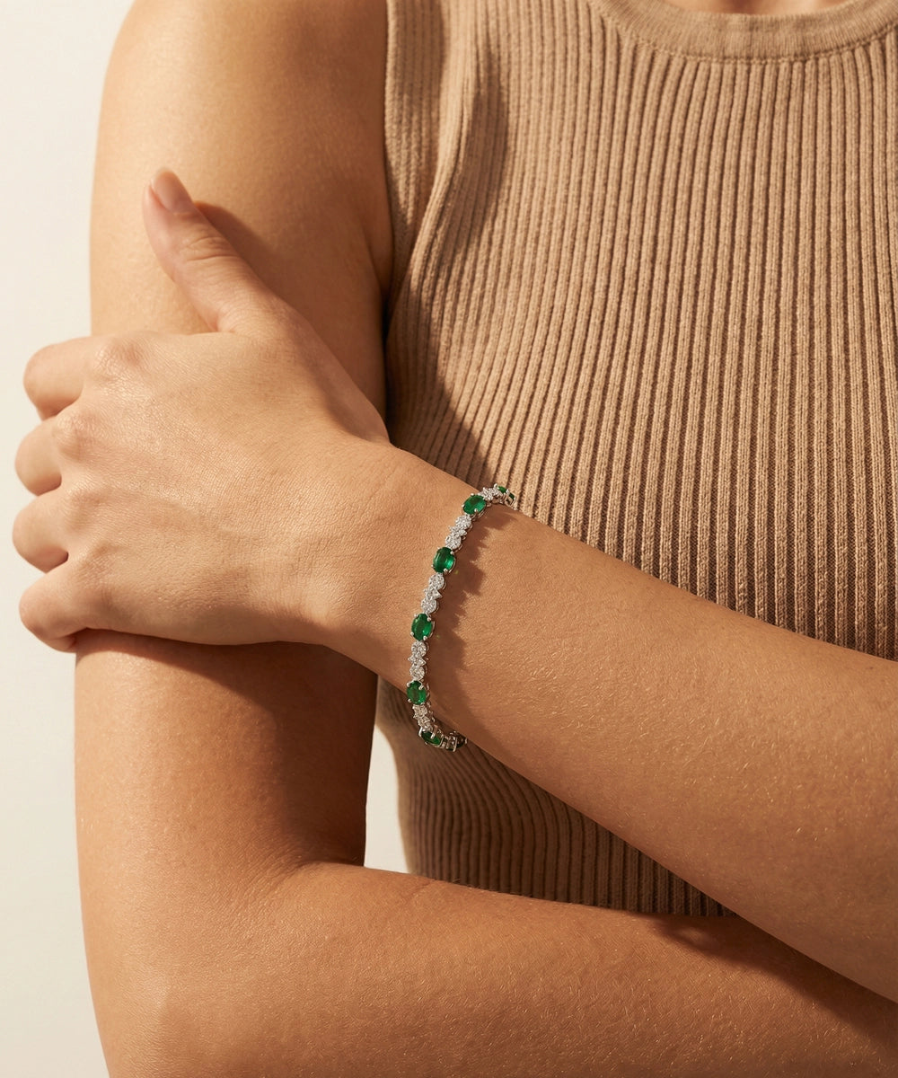 Person wearing a bracelet with green gemstones on a neutral background