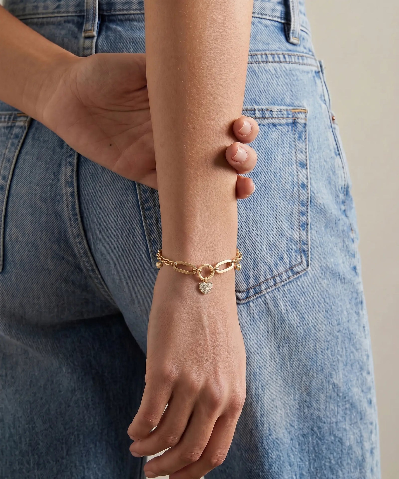Gold bracelet on a wrist with denim jeans