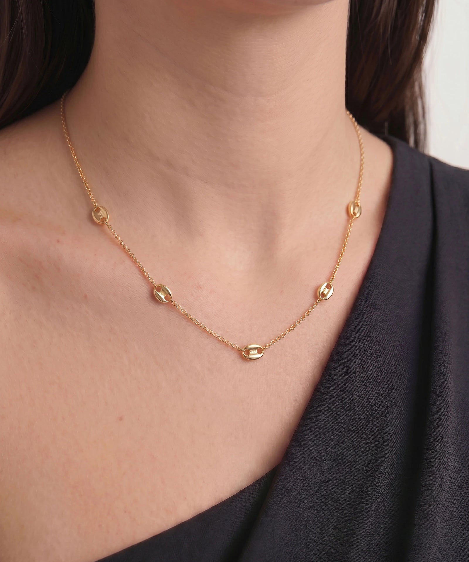 Gold necklace on a person wearing a black top