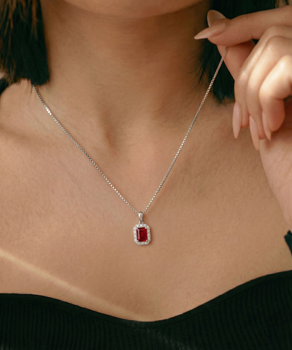 Necklace with a red gemstone pendant worn by a person