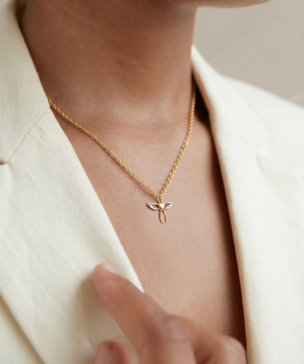 Gold necklace with a delicate pendant worn by a person in a cream blazer.