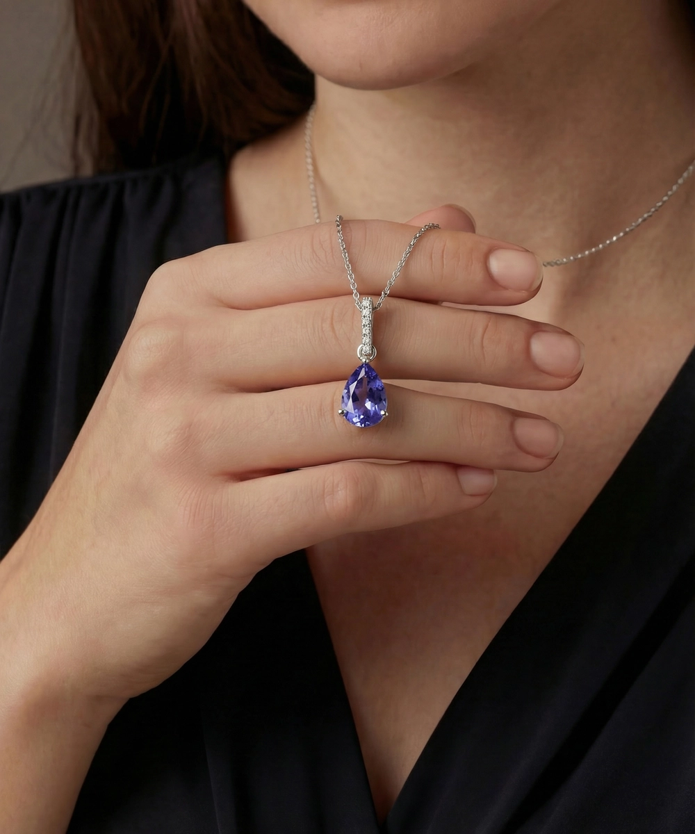 Person wearing a silver necklace with a blue gemstone pendant