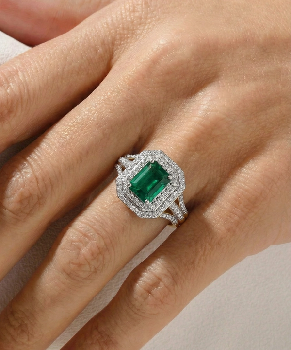 Emerald ring on a hand against a neutral background
