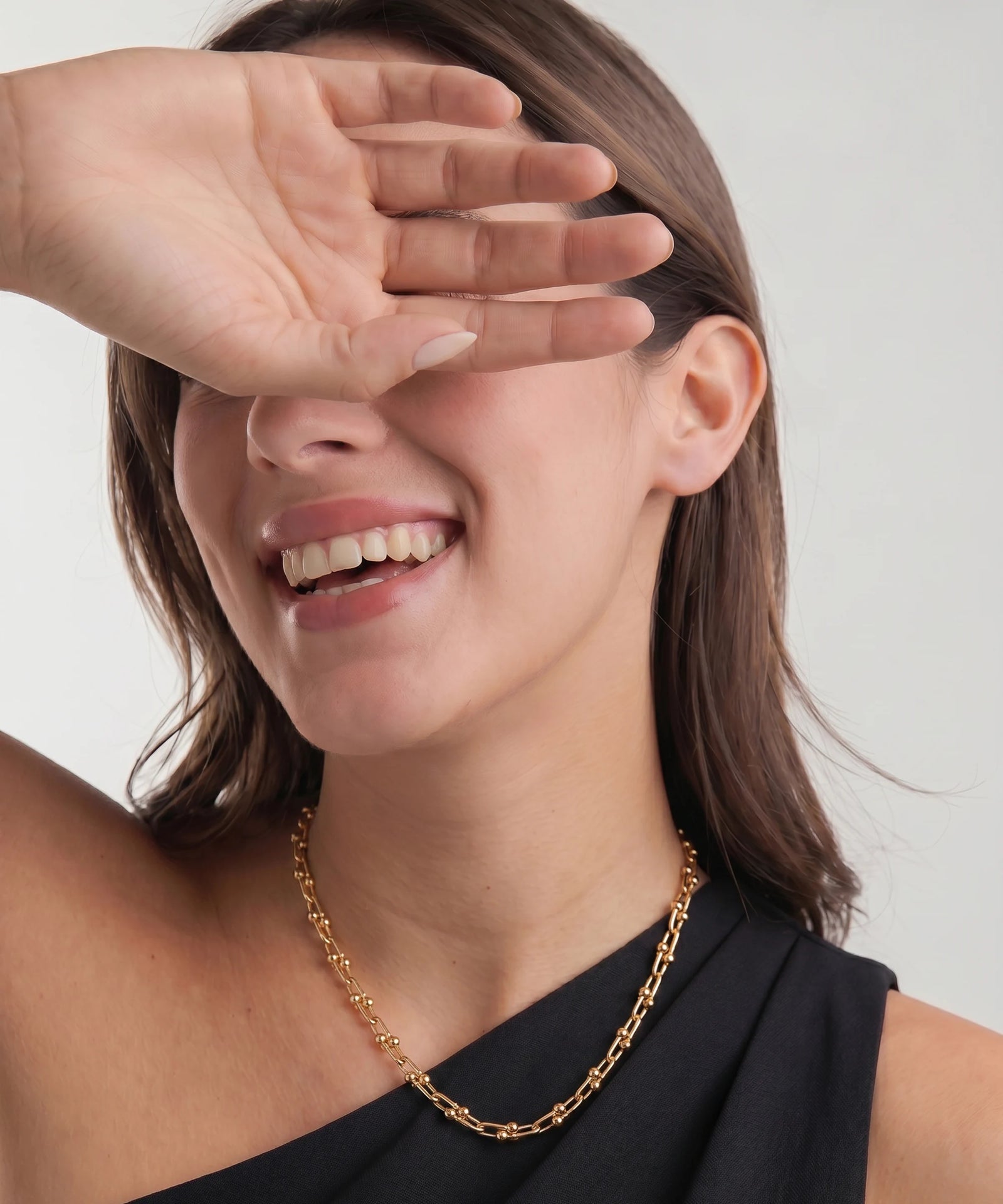 Woman wearing a gold chain necklace with a neutral background