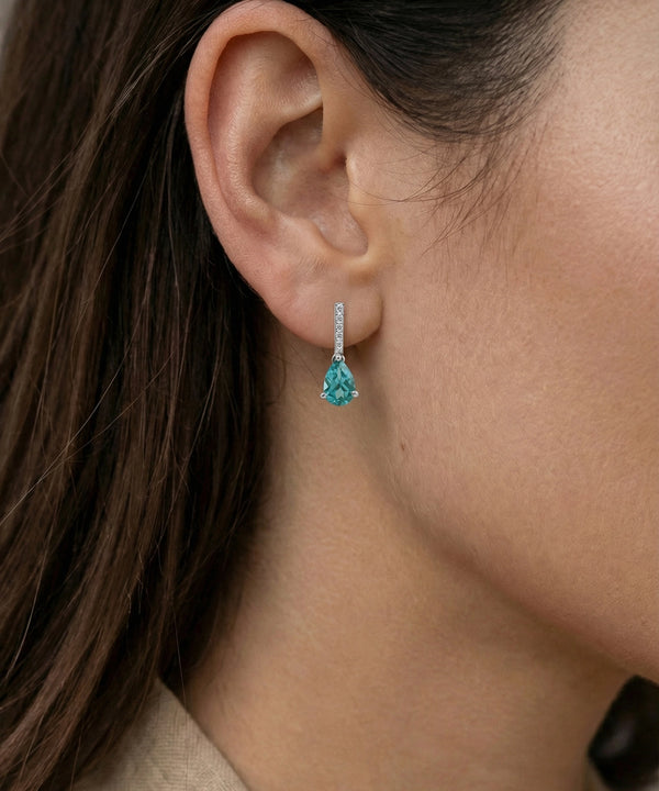 Close-up of an ear wearing a turquoise teardrop earring.