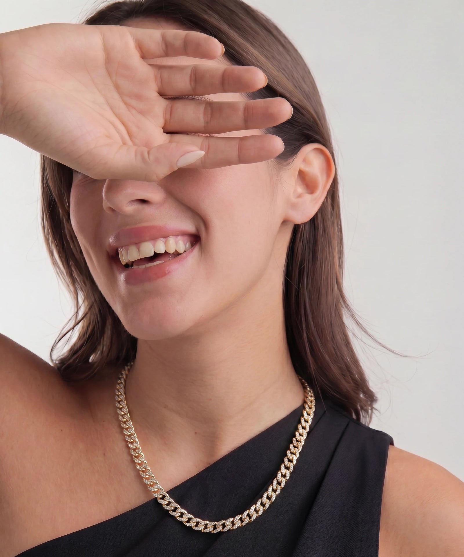 Woman wearing a gold chain necklace with a plain background