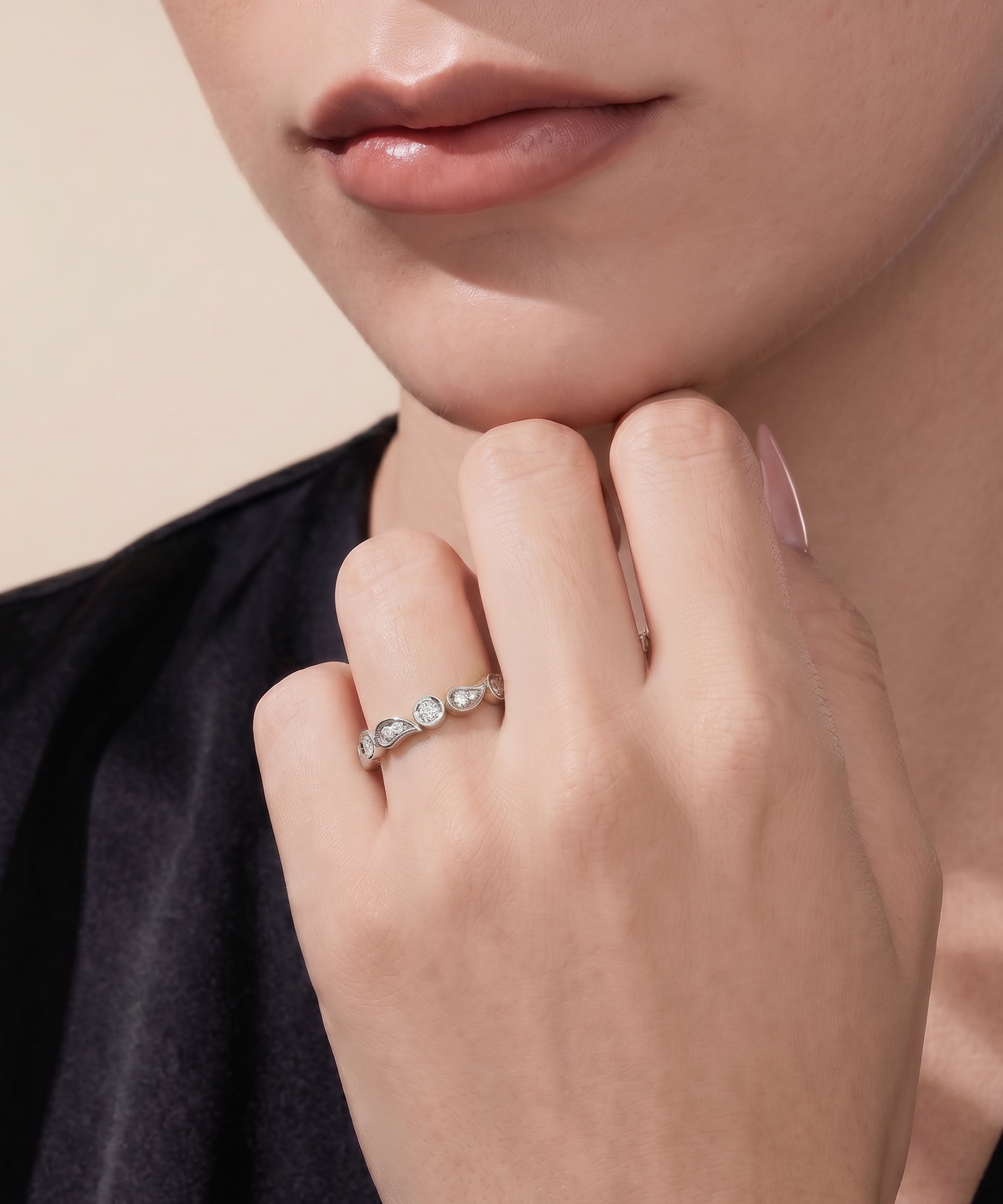 A close-up lifestyle shot of a model wearing a delicate silver ring with three small round-cut clear gemstones on her finger.