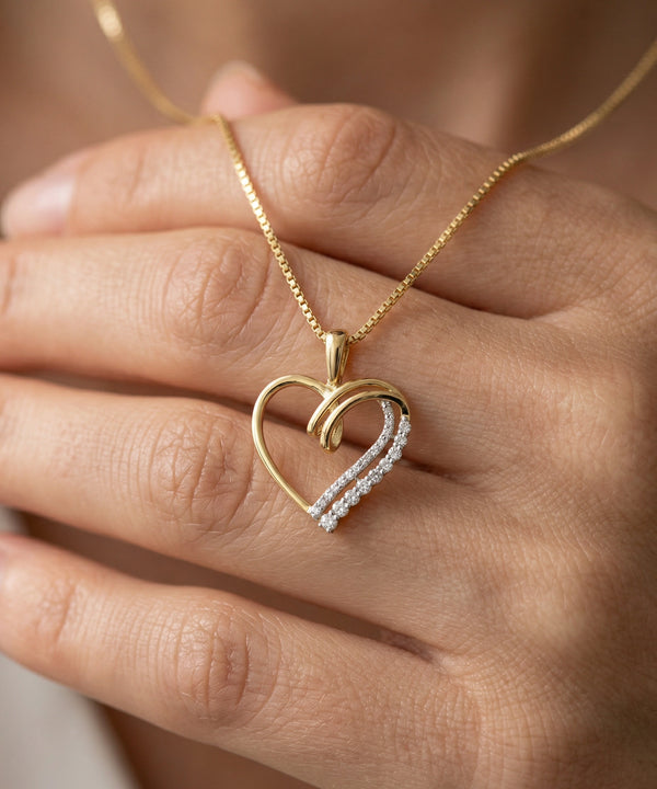Gold necklace with a heart-shaped pendant on a hand