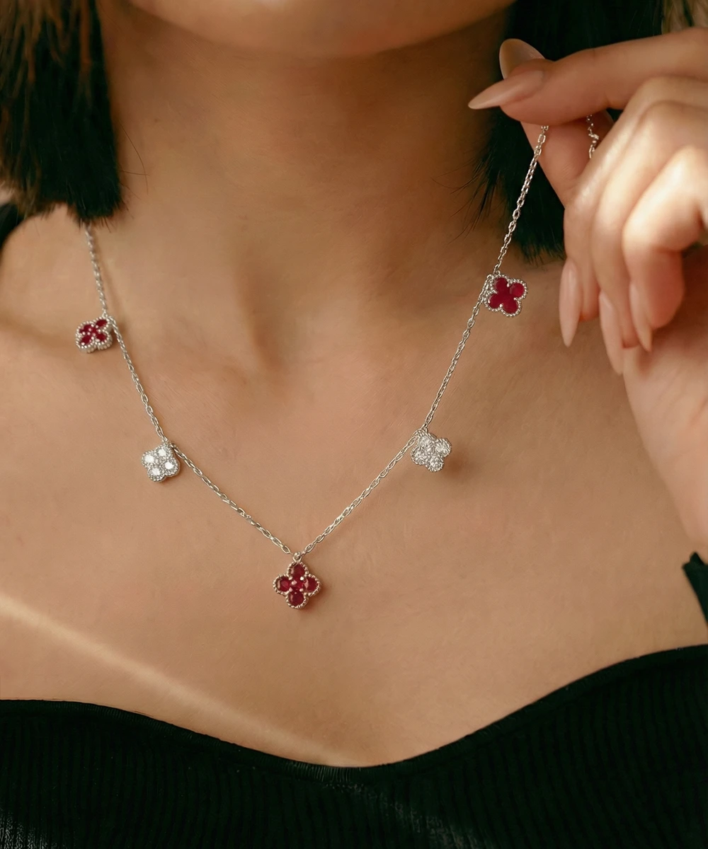 Necklace with floral pendants being worn and adjusted by a person.