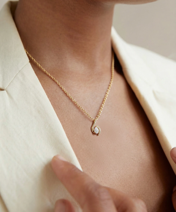 Necklace with a pendant worn by a person in a light-colored outfit