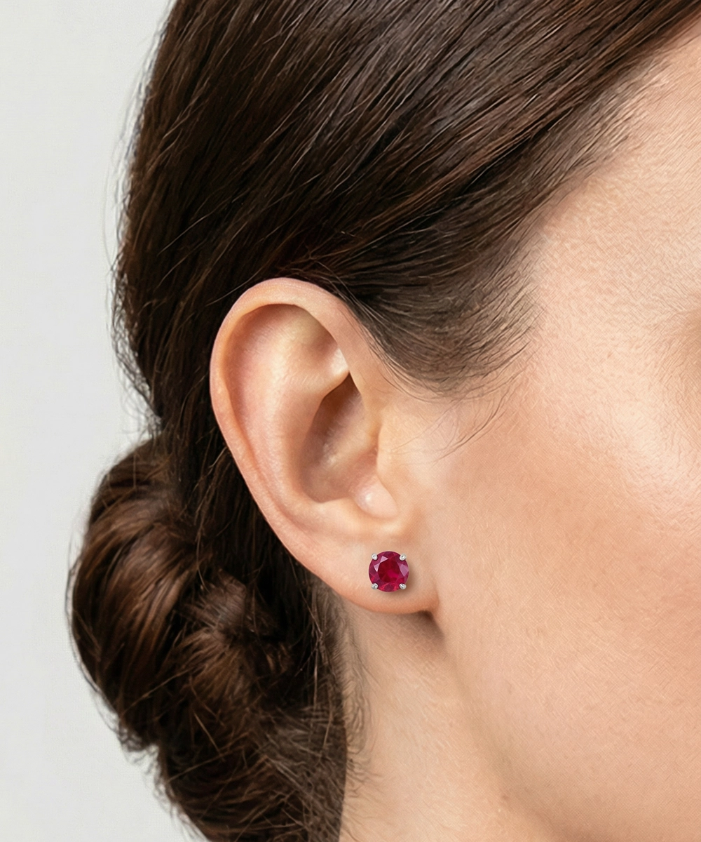 Close-up of an ear wearing a red gemstone earring with a blurred background