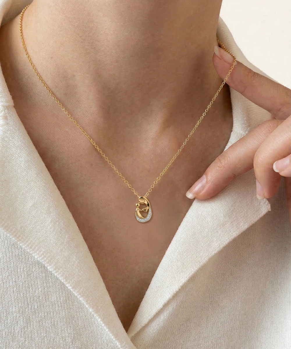 Gold necklace with a pendant worn by a person against a neutral background