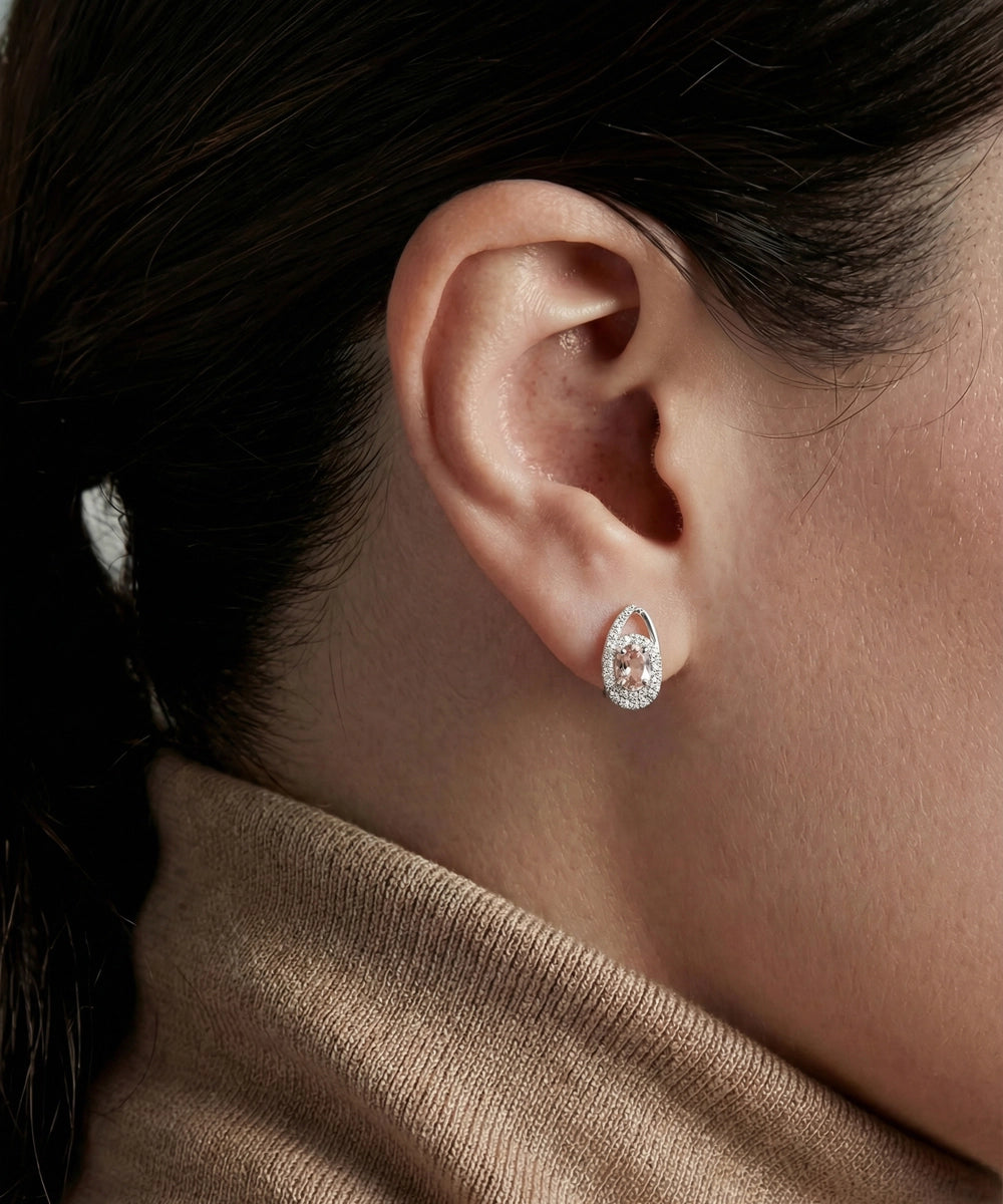 Close-up of a person wearing diamond earrings with a neutral background