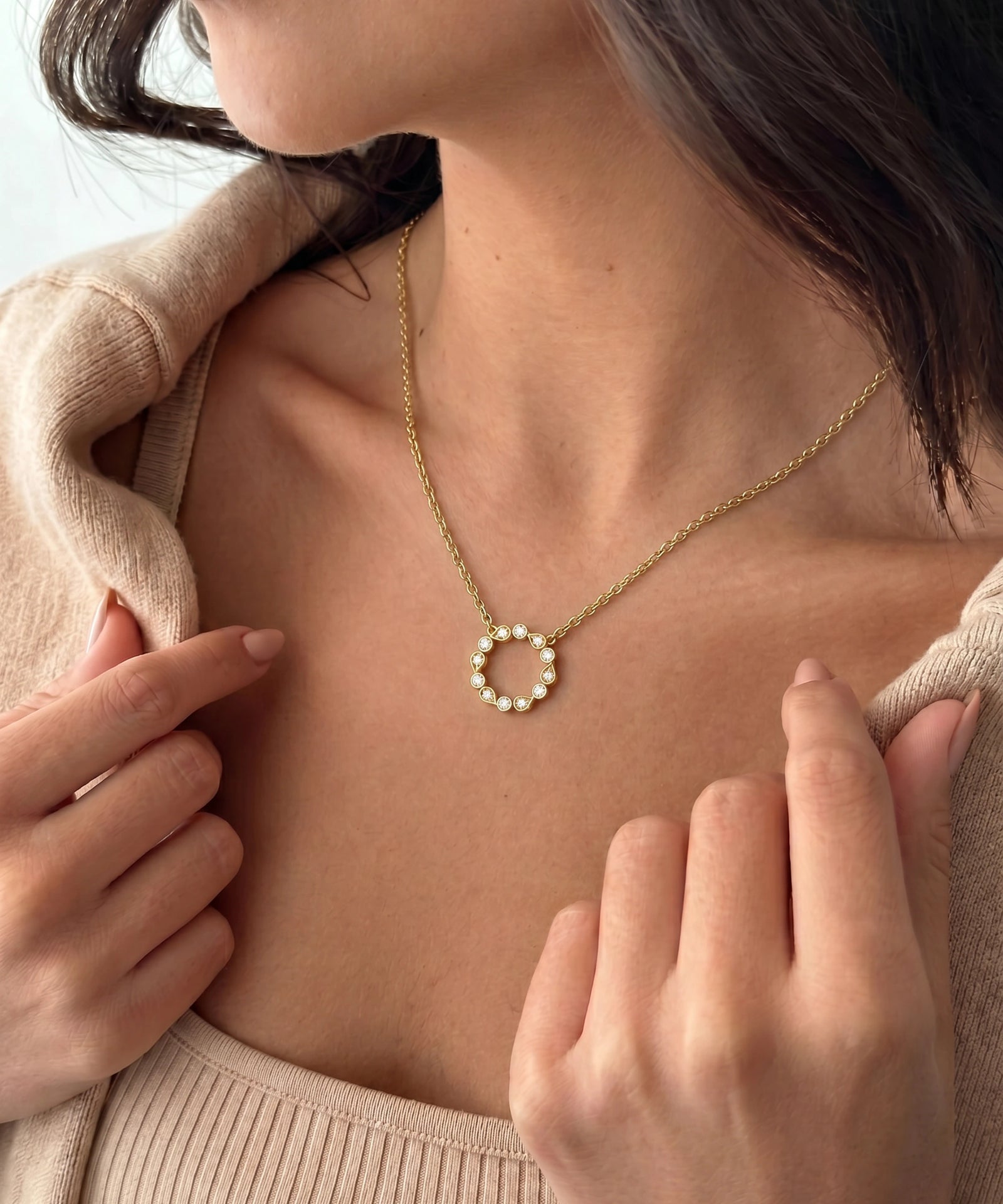 A close-up of a woman wearing a delicate gold chain necklace with a butterfly pendant. The butterfly is detailed with small pink and red gemstones.