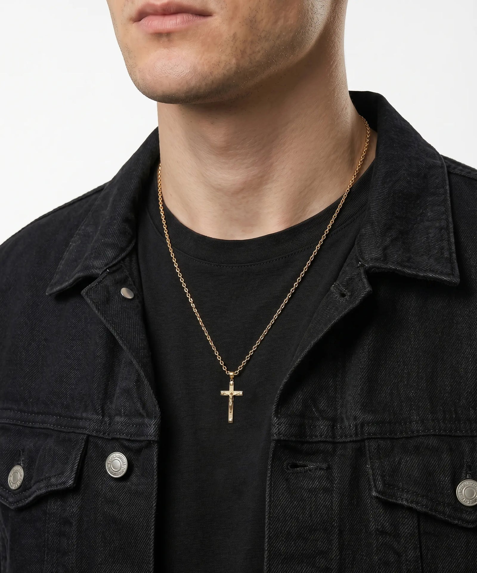 Man wearing a gold necklace with a cross pendant on a plain background