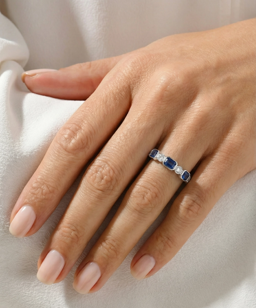 Hand wearing a ring with red gemstones on a light fabric background