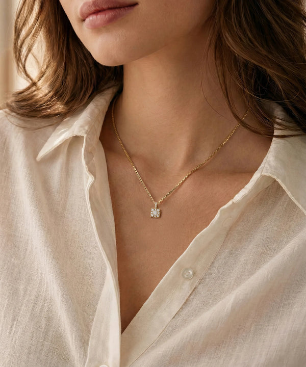 Close-up of a person wearing a gold necklace with a diamond pendant, set against a neutral background.