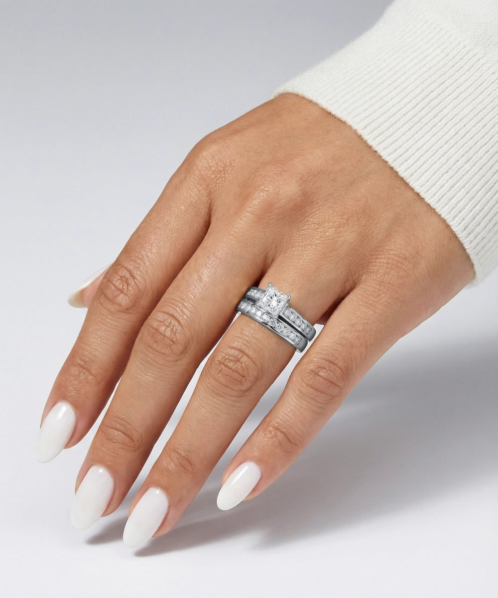 Hand wearing a silver ring with a diamond on a light gray background