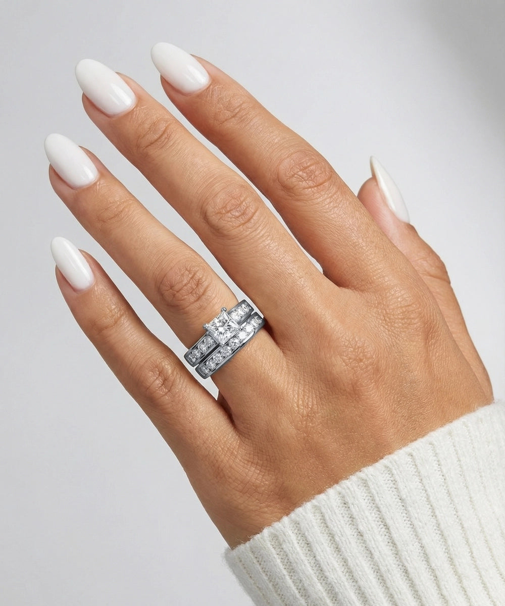 Hand wearing a diamond ring with a plain background