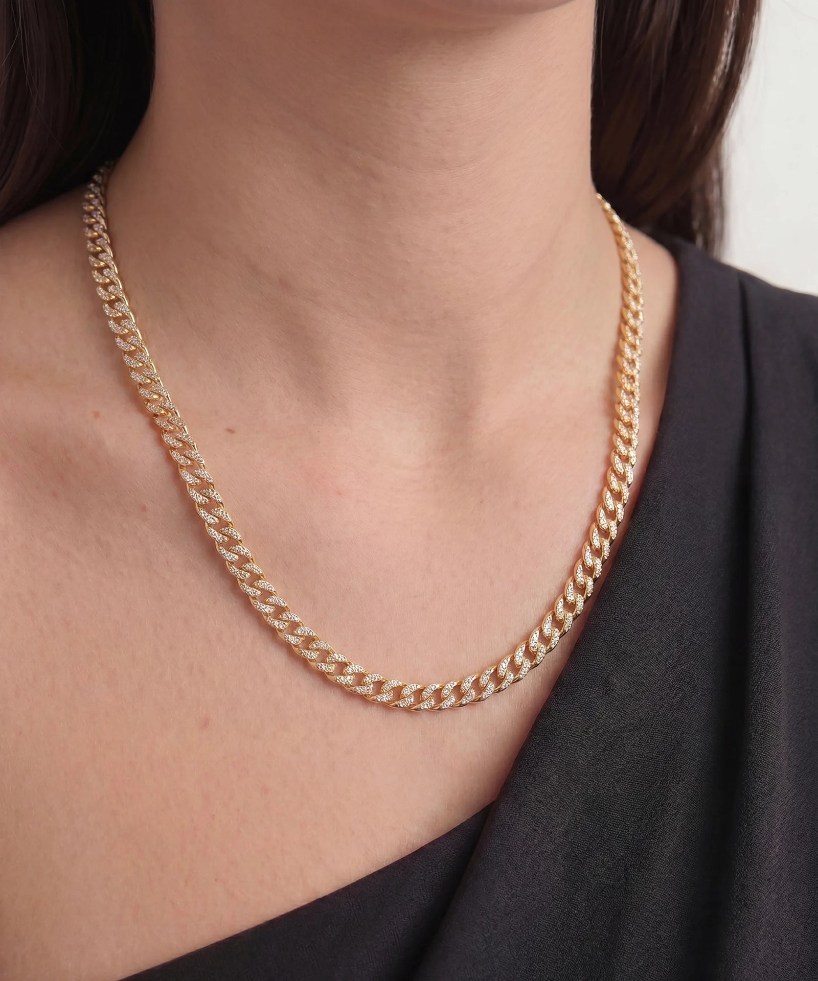 Gold chain necklace worn by a person with a blurred background
